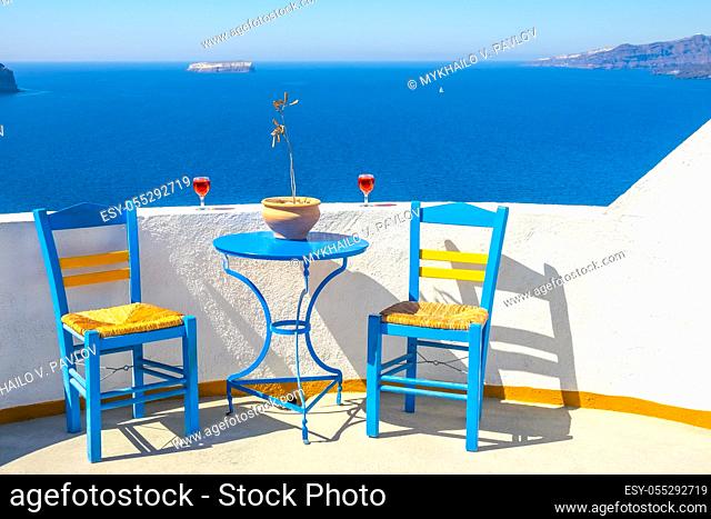 Greece. Thira island. Sunny seascape from a cafe in Oia. Two chairs and two glasses of wine