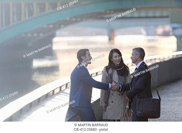 Businessmen handshaking at urban waterfront