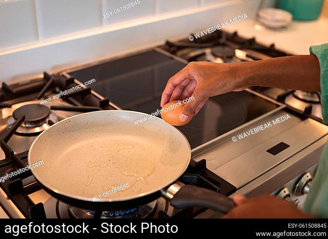 Mid section of woman cooking eggs in the kitchen