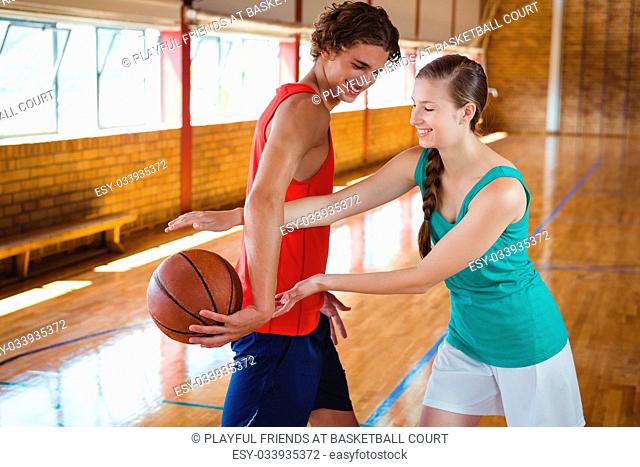 Playful friends practicing at basketball court