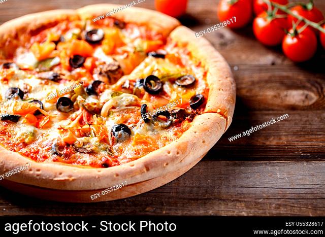 Vegeterian pizza with mushrooms and olives on wooden old table and fresh tomatos, green onion and chilli pepper on background