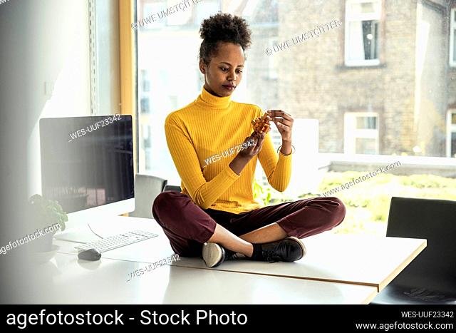 Female professional assembling wooden cube puzzle while sitting on desk in office