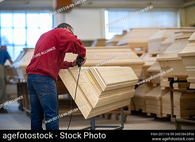 12 November 2020, Lower Saxony, Glandorf: An employee of the coffin manufacturer Schmidt-Hendker stands at a coffin lid and carves ornaments into the wood