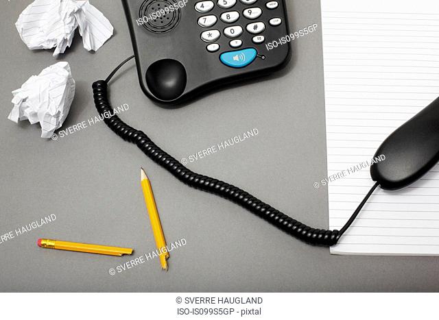Landline office phone off the hook with pencil and paper, high angle