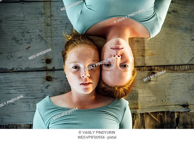 Redheaded twins lying on ground, looking at camera