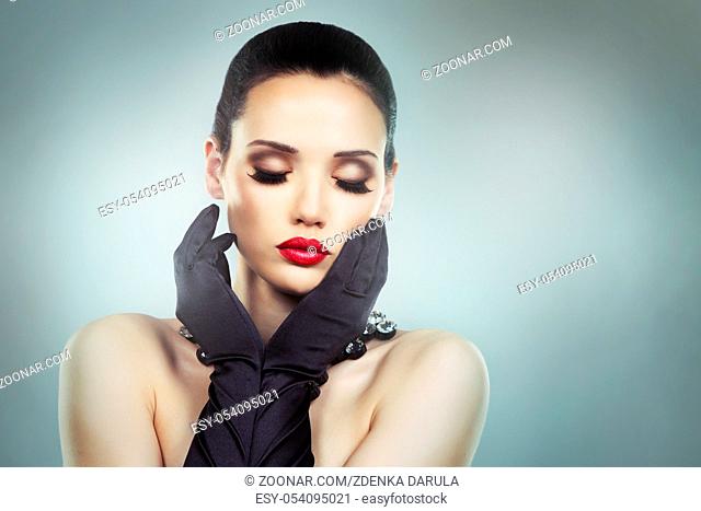 Upscale woman wearing jewellery and red lipstick on light background