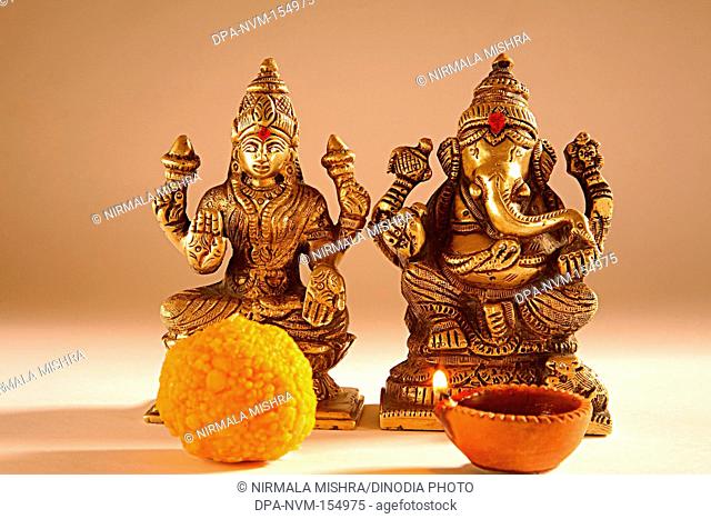 Diwali deepawali festival , shree lakshmi puja with god ganesh , sweets offered with oil lamp , India