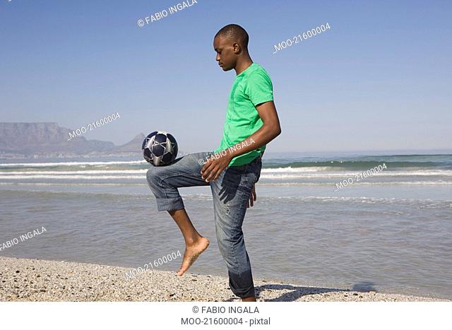 Young man playing soccer on beach