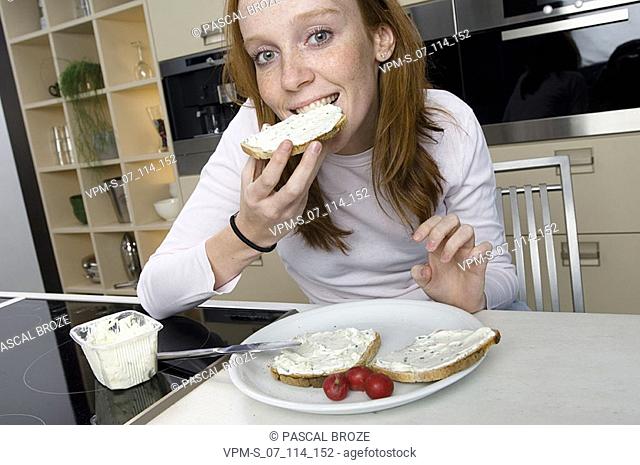 Portrait of a young woman eating a slice of bread