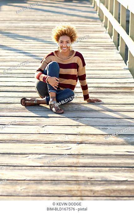 Black woman sitting on wooden boardwalk