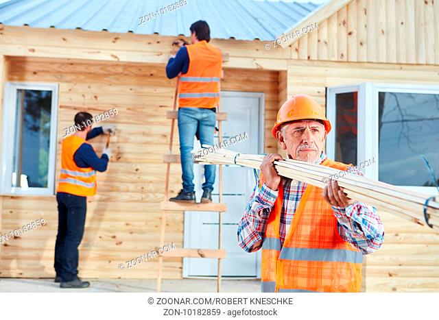 Handwerker bauen in Teamarbeit ein Holzhaus als Ferienhaus