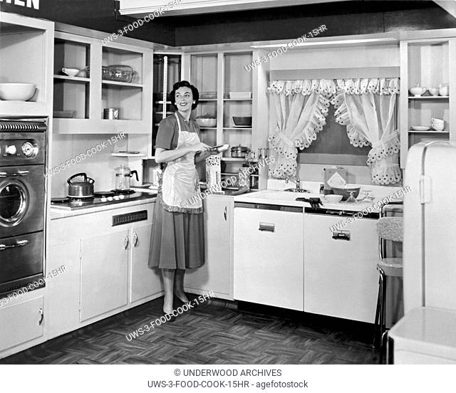 United States: c. 1950. .A woman wearing an apron in the kitchen of a model home making a sandwich with Wonder Bread