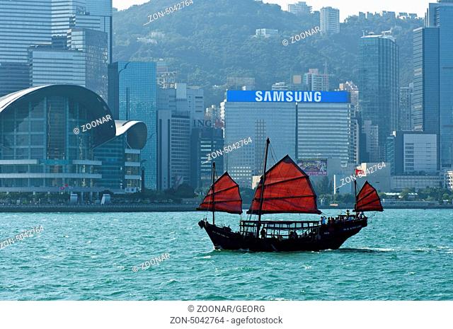 Traditionelle chinesische Dschunke segelt vor den Hochhäusern von Hongkong / Traditional Chinese junk sailing past the high-rising buildings of Hong Kong