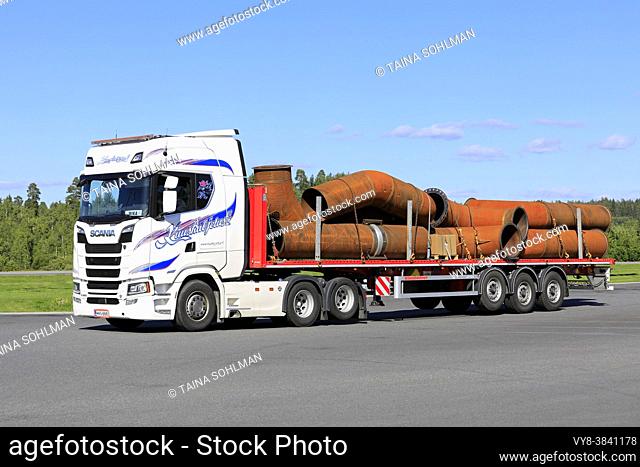 White Scania S 580 truck Kuuskuljetus Oy transports industrial pipes on flatbed trailer on a day of summer. Forssa, Finland. July 31, 2020