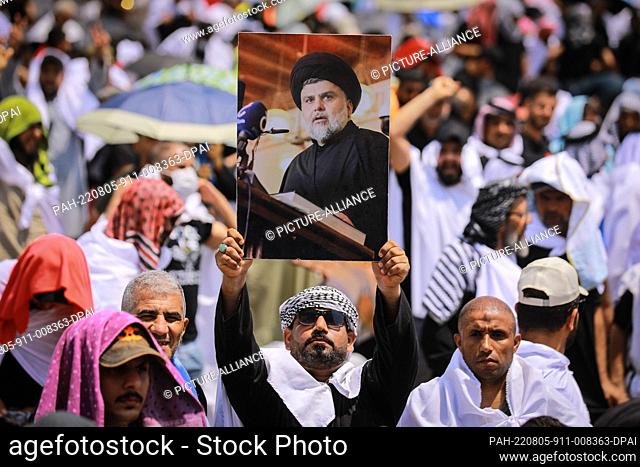 05 August 2022, Iraq, Baghdad: A supporter of Iraq's influential Shiite cleric Muqtada al-Sadr holds up his picture during Friday prayers at the Grand...