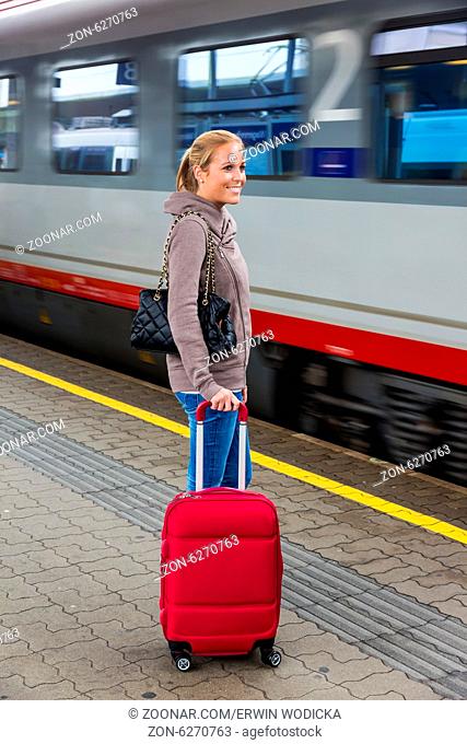 Eine junge Frau wartet auf einen Zug in einem Bahnhof. Zugfahrt in den Urlaub