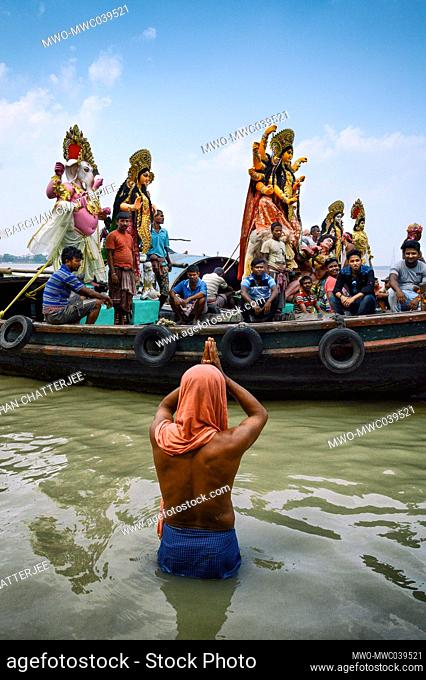 A man prays to an idol of Goddess Durga while being transported by boat over the Ganges River, ahead of the Durga puja celebration. Kolkata, India