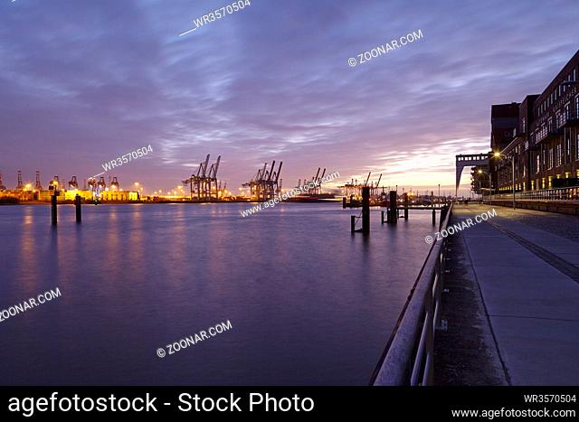 Der Hamburger Hafen am Abend mit den Containerverladebrücken als Silhouetten m Gegenlicht der Abenddämmerung fotografiert