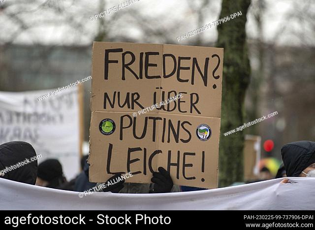 25 February 2023, Berlin: A participant in a rally on Pariser Platz demonstrates against the demonstration for negotiations with Russia at the Brandenburg Gate