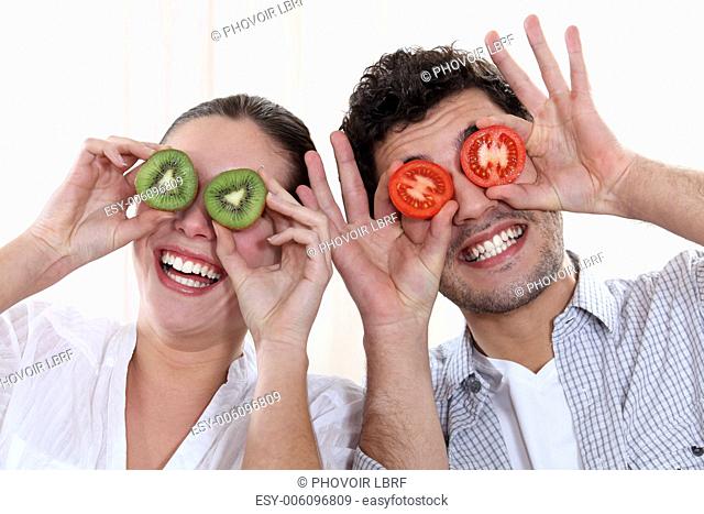 Funny couple covering their eyes with fruit