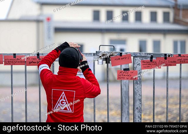 02 November 2023, Saxony-Anhalt, Eisleben: A trade unionist takes a photo at the factory gate of the toy and furniture manufacturer Haba in Eisleben of slips of...