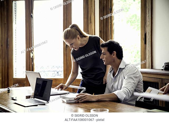 Colleagues working together on laptop computer in casual office