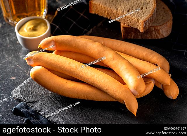 Smoked frankfurter sausages on cutting board on black table
