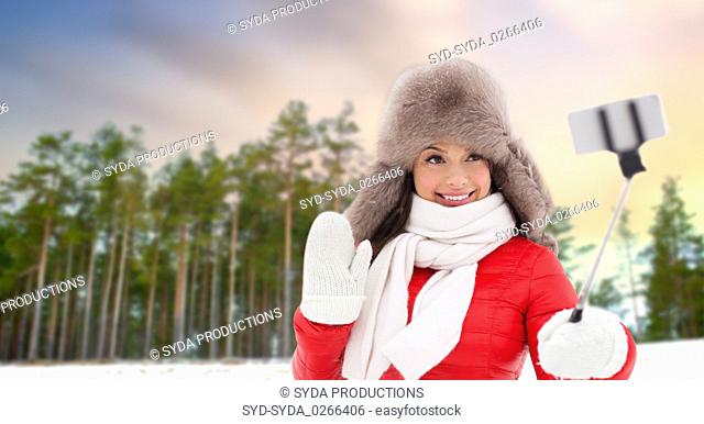 happy woman taking selfie over winter forest