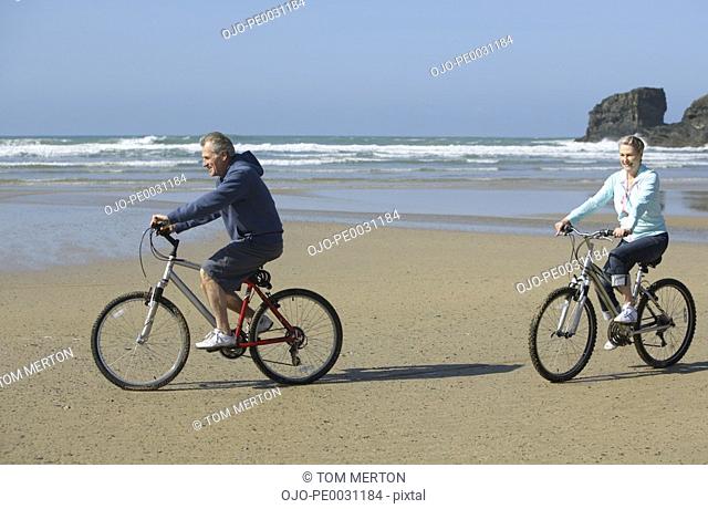 a couple riding bikes at the beach