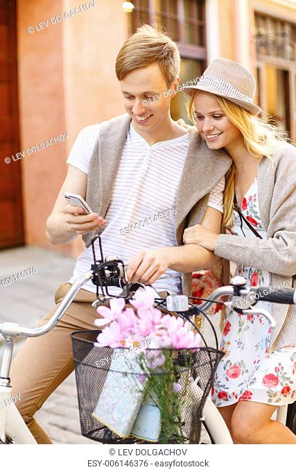 summer holidays, bikes, love, relationship, navigation, gps and dating concept - couple with bicycles and smartphone in the city