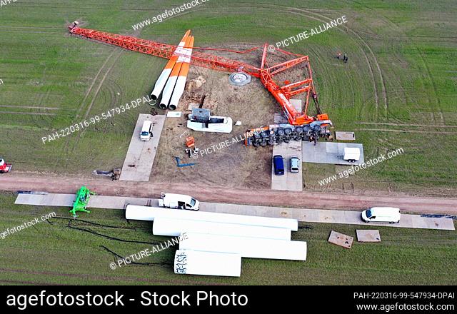 16 March 2022, Brandenburg, Elsterwerda: A large truck-mounted crane lies on its side at a construction site for a wind turbine at the wind farm between...