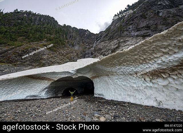 Hiker stretches his arms in the air, entrance to an ice cave of a glacier, Big Four Ice Caves, Okanogan-Wenatchee National Forest, Washington, USA