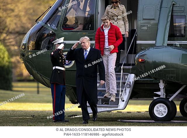 United States President Donald J. Trump salutes a Marine as he steps off of Marine One with first lady Melania Trump, and their son Barron Trump