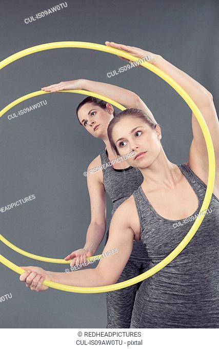 Young women practising with hula hoop, grey background
