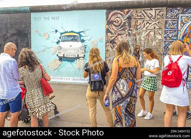 visitors at east side gallery, trabi car breaking through wall, friedrichshain-kreuzberg, berlin, germany