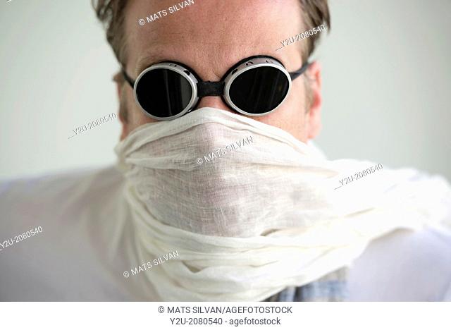 Man with sunglasses and a scarf cover his face