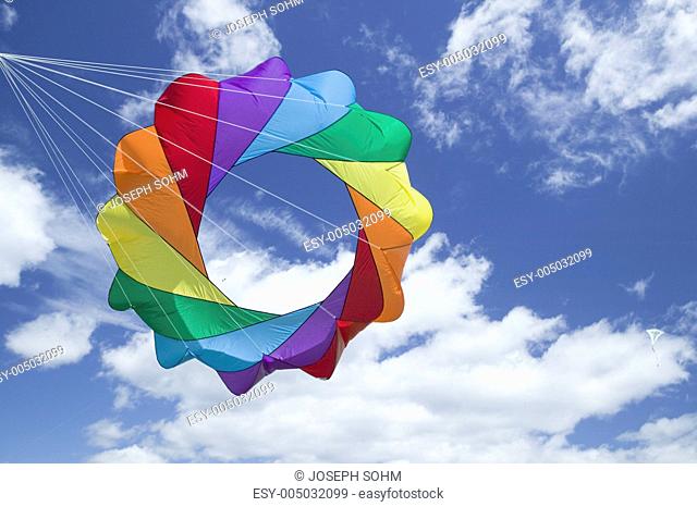 A rainbow colored kite flying in a blue sky with white puffy clouds on April 15, 2007, at the Santa Barbara Kite Festival, Santa Barbara City College