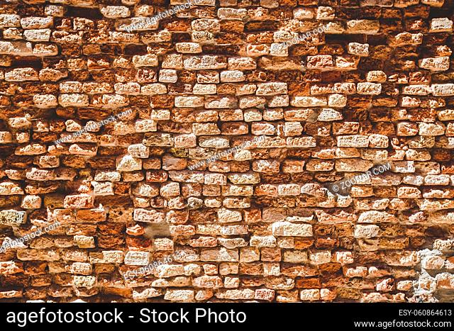Old brick wall texture. Weathered wall surface. Grungy orange brickwall. Red stonewall background. Shabby building facade Italian wall of an old house on sunny...