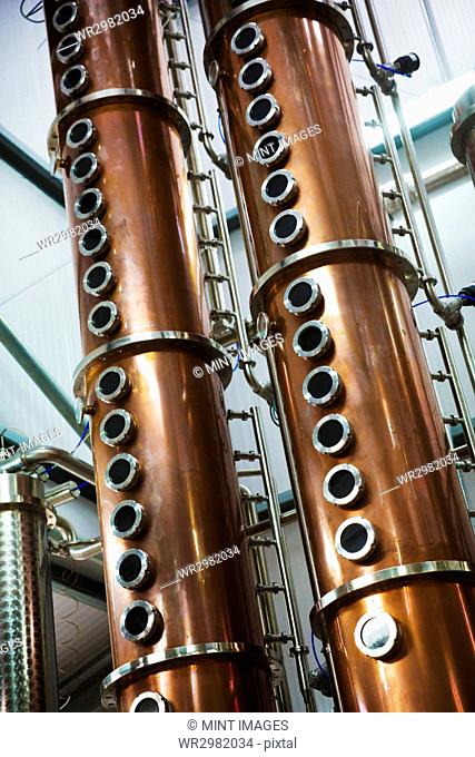 Tall copper distillery chambers in a brewery, brewing storage tanks in copper and steel