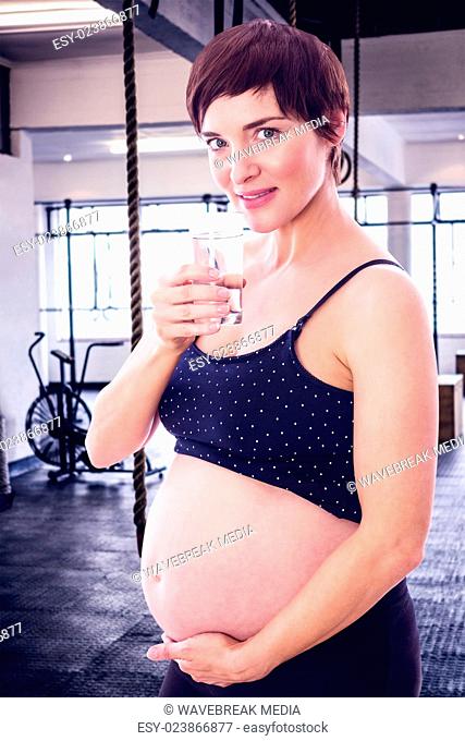 Composite image of pregnant woman drinking glass of water