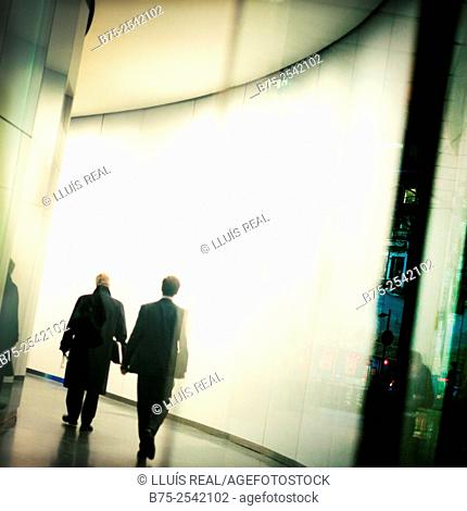 Backlit silhouette of two executives men walking down one corridor. City of London, England, UK, Europe