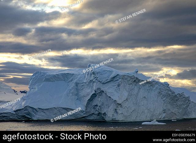 Warm sun rays through cloud cover create beautiful light over iceberg near the South Pole