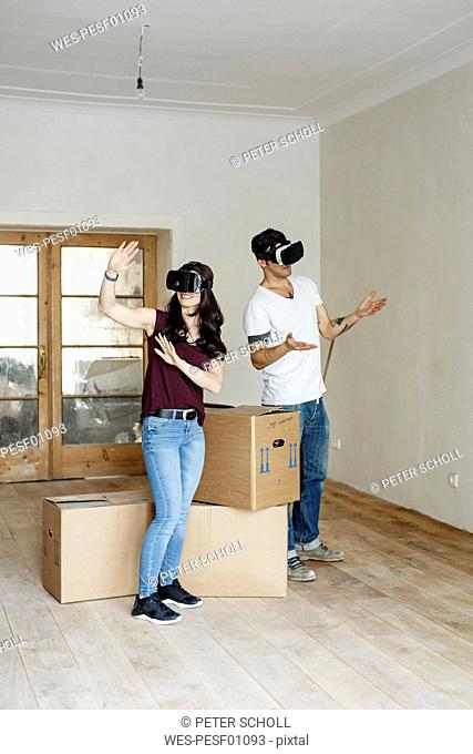 Couple moving into their new home, looking through VR glasses