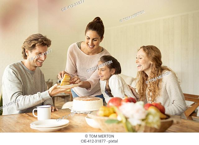 Woman serving cake to family at dining table
