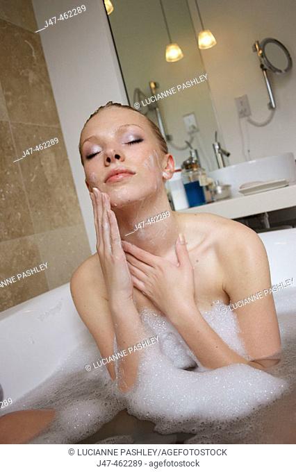 21 year old girl in the bath washing her face with closed eyes