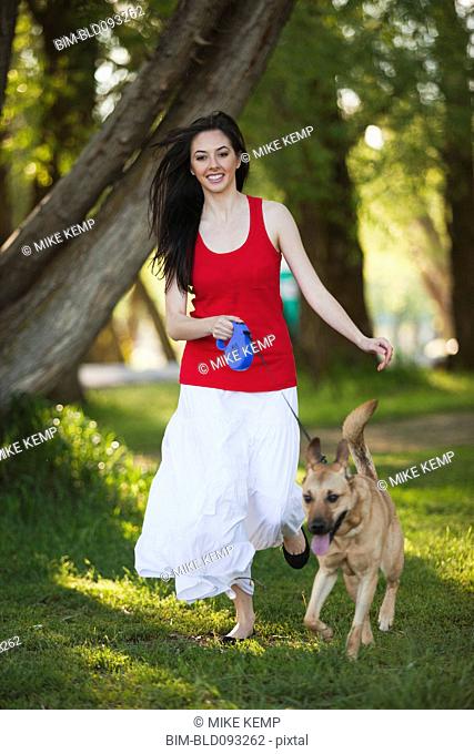 Caucasian woman walking dog in park