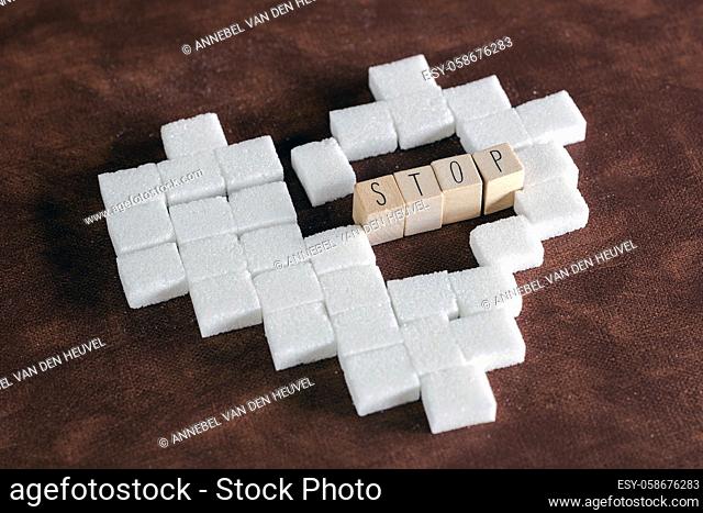 Sugar cubes in heart shape on brown background texture with Stop sign for diabetes. To stop diabetes, Health, sugar, junk food concept sweet modern design