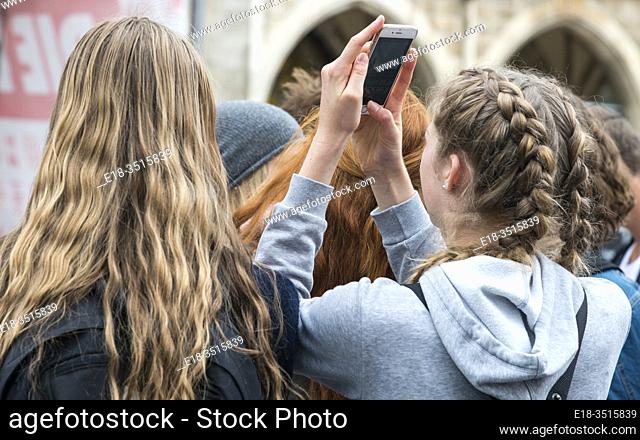 Germany, Munich. Marienplatz. Young, blonde haired girls watch the glockenspiel in the town square