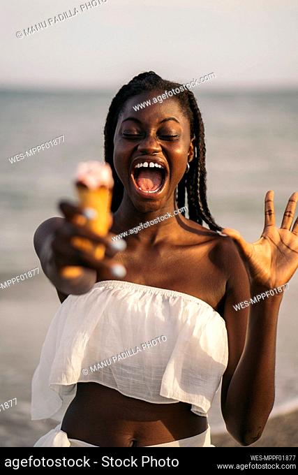 Happy teenage girl holding ice cream at beach