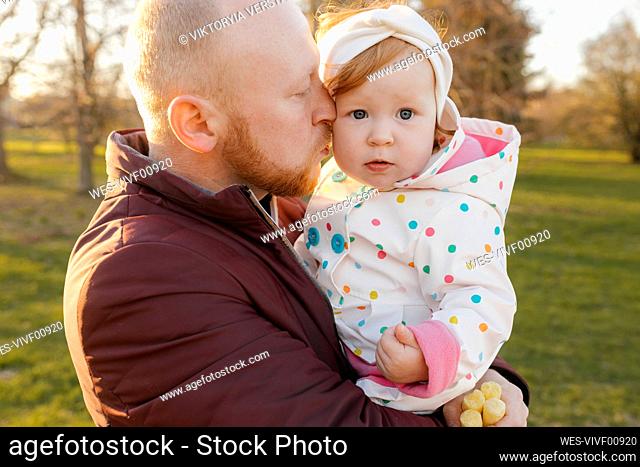 Father kissing daughter on cheek at park
